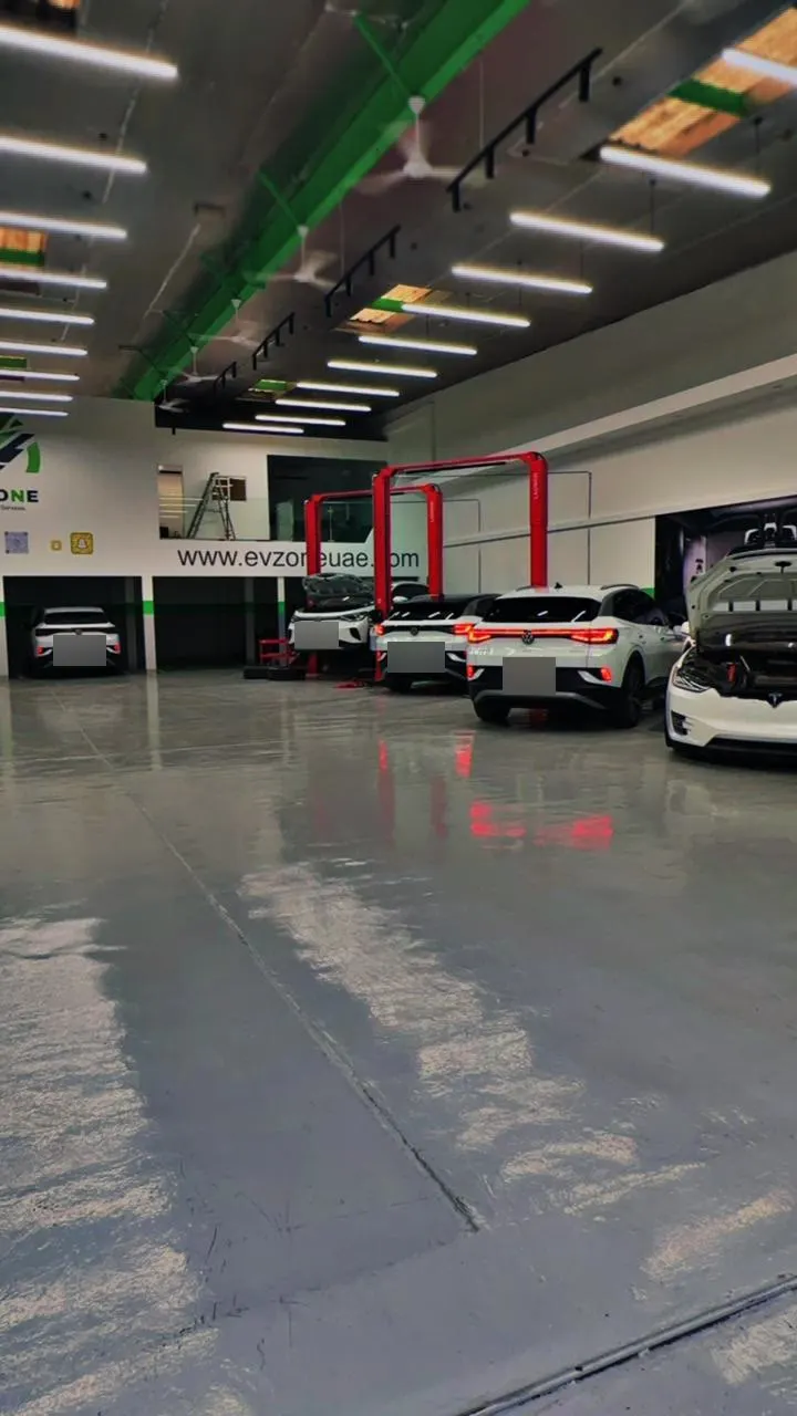 The EV Zone bay line: several VW ID.4 cars and a Tesla Model X with its bonnet up, in front of two red two-post lifts