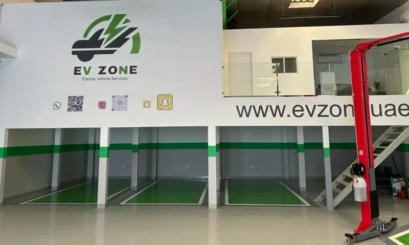 Inside the EV Zone workshop: three service bays with green floor markings, the EV Zone wall sign and a two-post lift