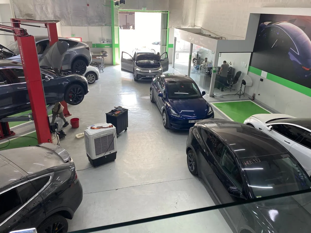 Several electric cars on lifts in the EV Zone workshop in Sharjah