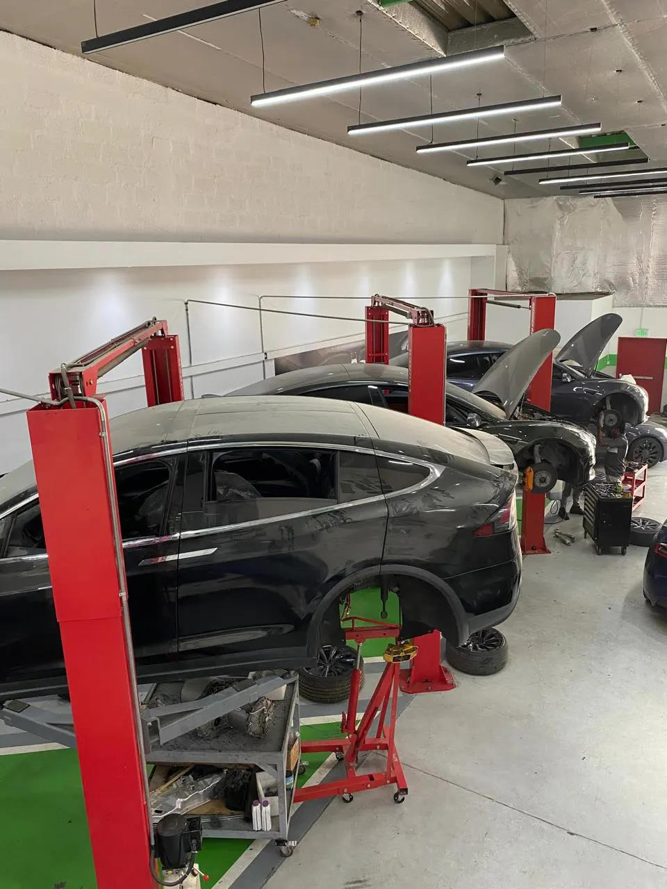 ثلاث سيارات تسلا مرفوعة على الرافعات في ورشة EV Zone بالشارقة