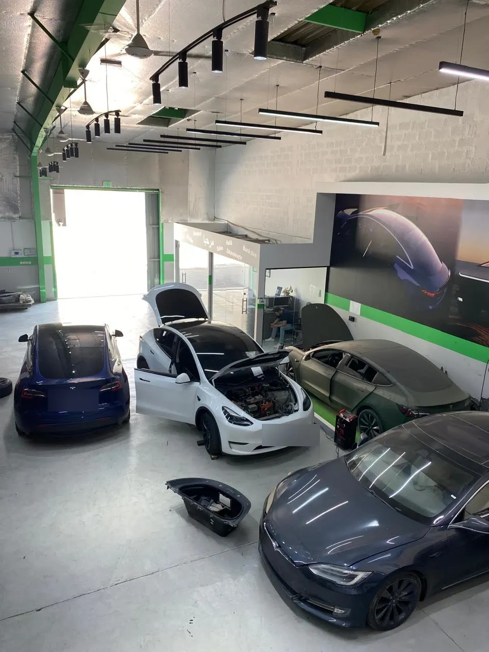 أربع سيارات تسلا على أرضية ورشة EV Zone في انتظار الفحص
